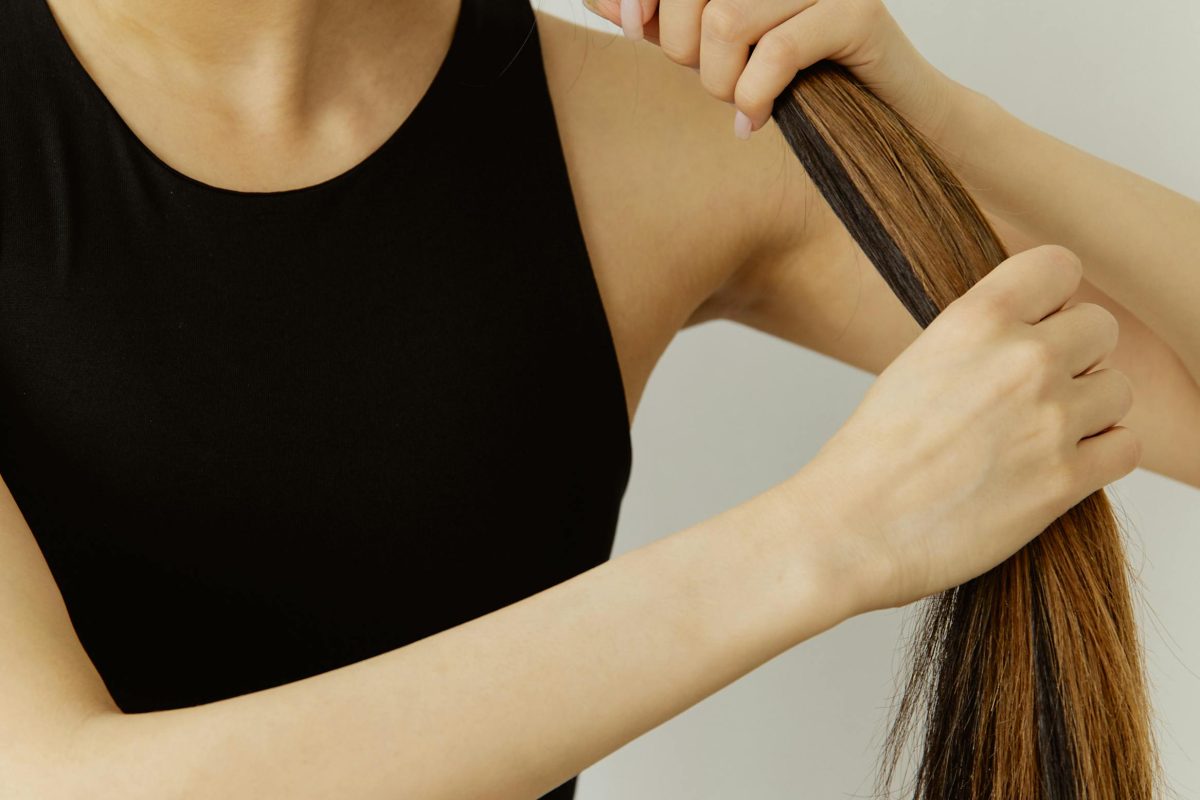 Woman holding her long, smooth strands to showcase healthy hair texture and shine.