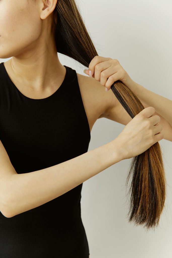 Woman holding her long, smooth strands to showcase healthy hair texture and shine.