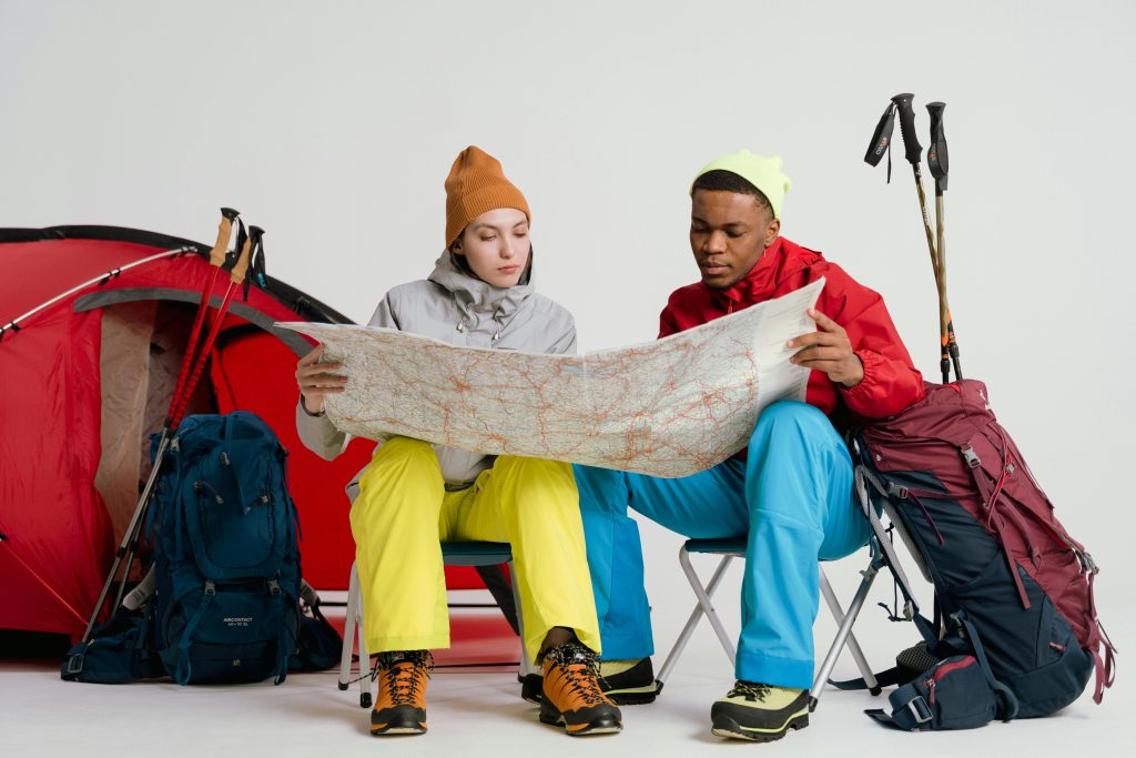 “Two people with backpacks examining a map during a winter outdoor trip.”